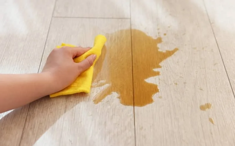 Wiping a spill on vinyl kitchen floor with a cloth